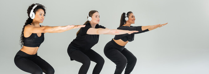 Women performing squats while wearing headphones in a bright fitness studio