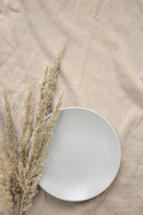 Ceramic plate with dried spikelets on a beige tablecloth. Eco natural concept. Mock up.