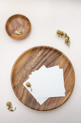 Blank white business card mockup on wooden plate. Beige backgound with dry hop cones. Modern template. Branding identity. Natural autumn, fall design. Flat lay, top view.