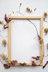 Autumn composition. Hop cones, dried leaves, wooden photo frame on white background. Autumn, fall concept. Flat lay, top view, copy space