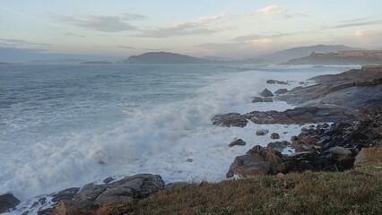 Stunning coastal view with waves crashing against rocky shores under a serene sky, capturing the natural beauty and tranquility of the seascape. Baiona - Galicia - Spain