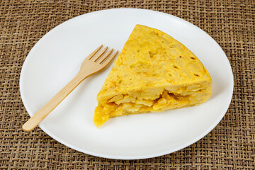 Spanish omelette with potatoes and eggs, served on a white plate with a wooden fork.