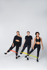 Three strong women engaging in a fitness workout with resistance bands indoors