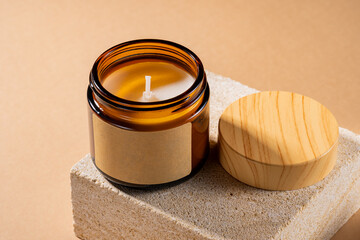 Mock-up of aroma soy candle in amber glass jar on natural stone pedestal. Scented cozy atmosphere...