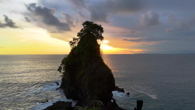 aerial view of sideways movement of rock cliffs in the sea at sunset