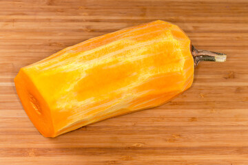 Half of butternut squash peeled from skin on wooden surface