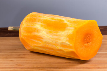 Half of butternut squash peeled from skin on wooden surface