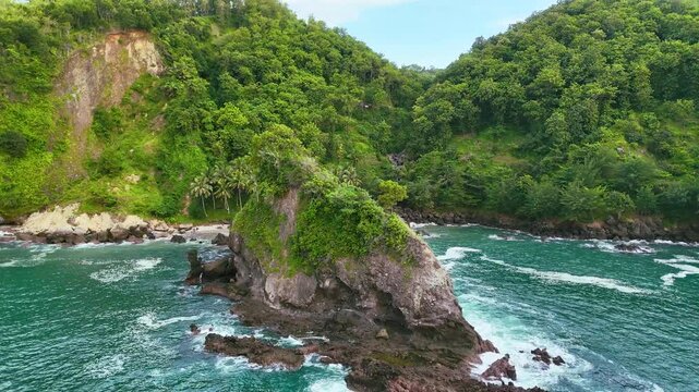 vertical motion backward aerial view of an island and rock cliffs in the blue sea