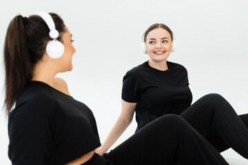 Two women enjoying a fitness session together in stylish sportswear while listening to music