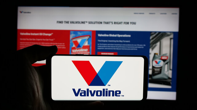 Stuttgart, Germany - 01-31-2025: Person holding cellphone with logo of American automotive services company Valvoline Inc. on screen in front of webpage. Focus on phone display.