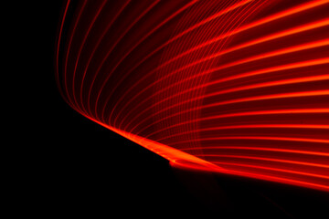 Vibrant red light streaks are dynamically creating intricate patterns and shapes against a...