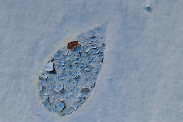 A faded blue metal surface with visible cracks and peeling paint