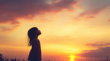 Child gazing at a vibrant sunset, embracing nature and tranquility. Perfect moment encapsulating outdoor serenity and peacefulness.