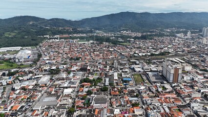 Visão aérea do centro urbano e da serra na cidade de Mogi das Cruzes, SP, mostrando a paisagem que une a urbanização com a natureza, destacando a cidade e as montanhas ao fundo © RNL Fotografia