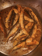 Crispy fried sardines in a pan, showcasing traditional italian seafood cooking from bibione, italy, during a warm july evening