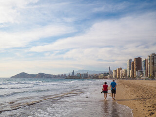 Pareja paseando solos en la playa de Benidorm