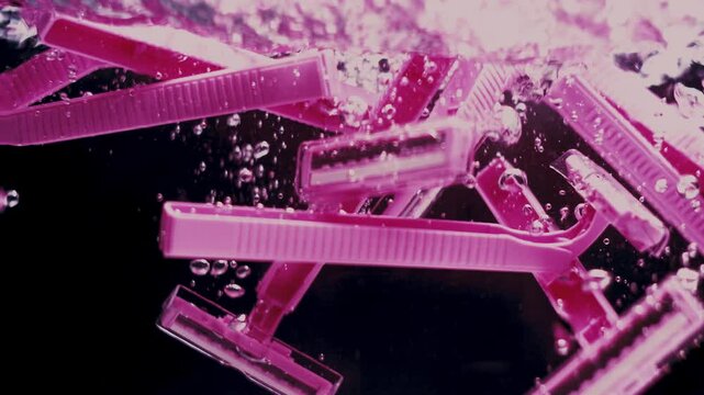 Pink razers fall in water in slow motion.