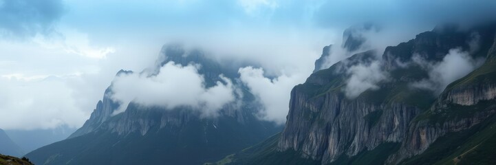 Fototapeta premium Towering mountain peaks shrouded in mist and cloud with a secluded valley below, tranquility, nature, serenity