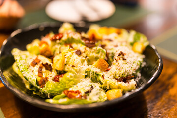 A bowl of fresh caesar salad with bacon, croutons and cheese