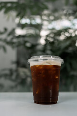 Selective focus of iced dark cold brew americano coffee in plastic cup.