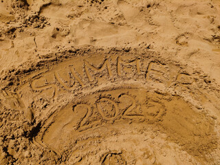 The words summer 2025 are written in the sand on bibione beach, creating anticipation for future...