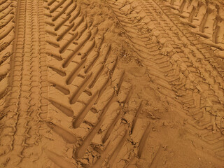 Close up of tire tracks imprinted on the golden sand of a beach in bibione, italy, creating a...
