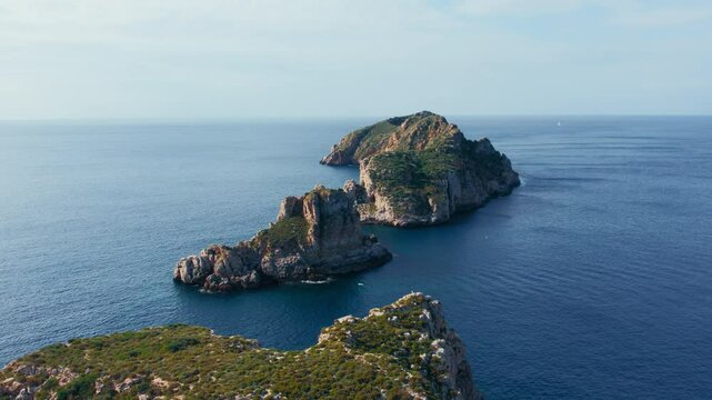 Aerial drone flyover footage of rock formations and cliffs of Islas Malgrats, Santa Ponca in Mallorca, Spain. Serene Mediterranean Sea, seagulls fly. Tourist sailing destination for summer holiday