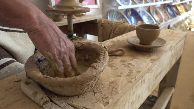 Artist dips finger in water while creating beautiful ceramics by hand, culture and traditions in Guellala Tunisia
