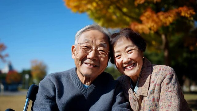 Un couple de personnes &acirc;g&eacute;es asiatiques assis au soleil dans un parc avec des arbres &agrave; l'automne.