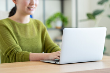 Fototapeta premium リビングでパソコンを使う若い女性