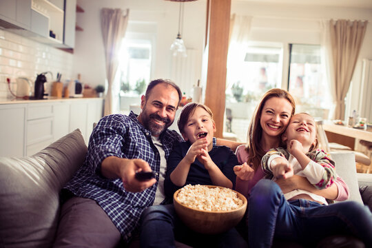 Young family watching a movie in the living room on the tv - Powered by Adobe