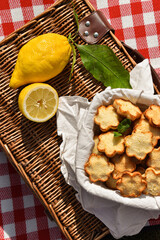 Homemade lemon and coconut crunchy cookies made for a picnic/lunch. Served on a picnic basket with fresh lemons.