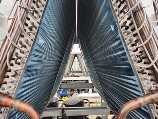 Large industrial air conditioning unit condenser coils showing the cooling fins and copper pipes,...