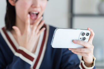 リビングでスマホを見る若い女性