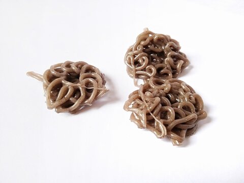 Three raw brown curly cracker doughs (kerupuk mie mentah) isolated on a plain white background.