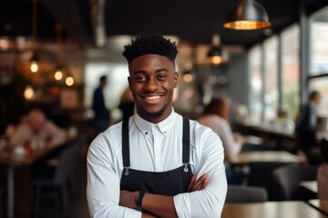 Fototapeta premium Smiling portrait of a young male African American waitress in cafe