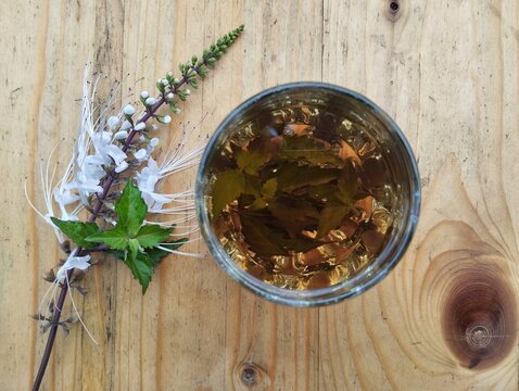 Boiled water cat whiskers leaves in glass with top view angle on wooden table, healthy drink lifestyle 