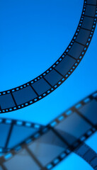 Fototapeta premium film strip and film roll on blue background isolated for desktop wallpaper banner.film production media festivals concept, blurry foreground. with white shades