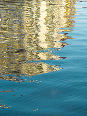 Abstract dark blue water reflex background. Reflection and abstract inspection elements in water. Yellow elements distorted in the lake. Rippled water texture. Disordered water surface. Water layout.