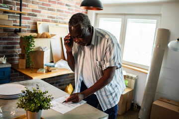 Senior man making moving arrangements on phone in new home