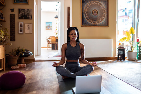 Woman practicing yoga at home in a sunlit room - Powered by Adobe