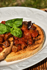 Bruschetta with fresh tomatoes, eggplant and basil on a picnic basket. Traditional Italian appetizer                                                                               