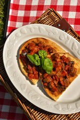 Bruschetta with fresh tomatoes, eggplant and basil on a picnic basket. Traditional Italian appetizer                                                                               