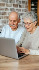An elderly couple is sitting together at a table, focused on a laptop, showcasing their engagement with technology and each other.