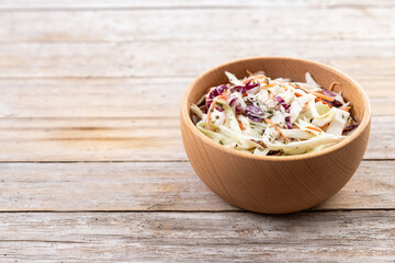Coleslaw salad in wooden bowl on wooden table. Copy space