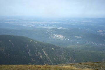 Panoramic mountain view over forested slopes and distant valleys with small settlements,...