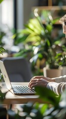 A close-up of a marketing strategist creating ad copy on a laptop in a modern office with plants and sleek furniture