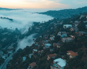 Aerial view of a city nestled in hills, partially covered by morning mist. Soft, muted light bathes the scene