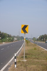 A warning sign to drivers to reduce speed and prepare to turn and a black and white reflector