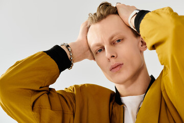 Handsome young man posing confidently in stylish yellow jacket against light backdrop